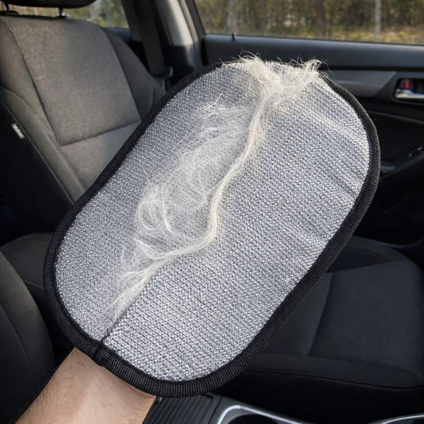 Arm holding the ShedMitt glove covered in white pet hair collected from a car seat
